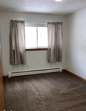 carpeted spare room featuring a baseboard radiator