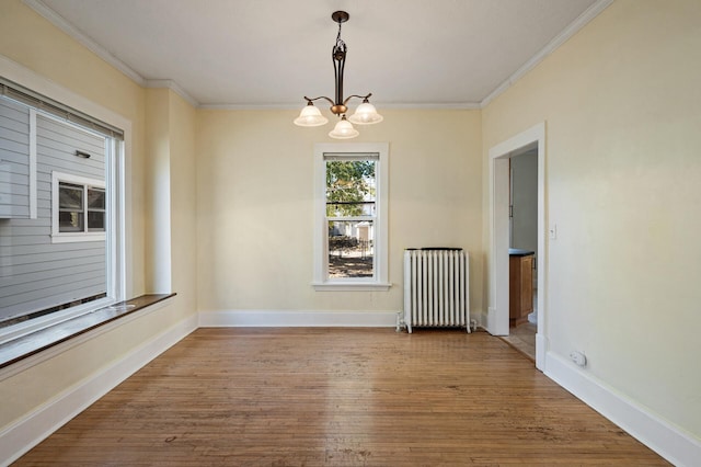 unfurnished dining area with ornamental molding, a notable chandelier, radiator heating unit, and wood-type flooring