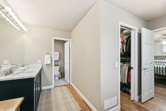 bathroom featuring ceiling fan, toilet, vanity, and wood-type flooring