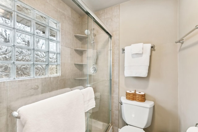 bathroom with a shower with shower door and toilet