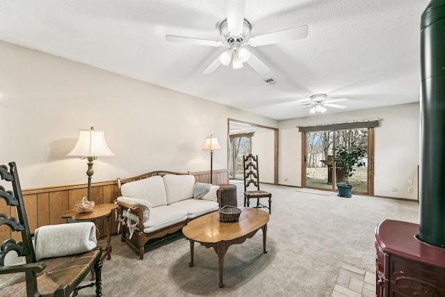 living room with wood walls, a textured ceiling, and light colored carpet