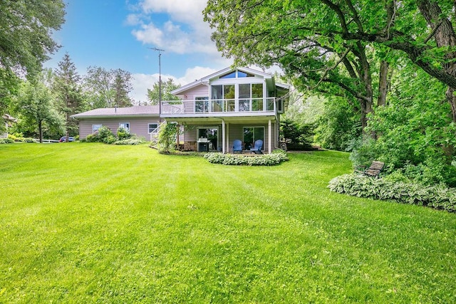 rear view of house featuring a deck, a yard, and a sunroom