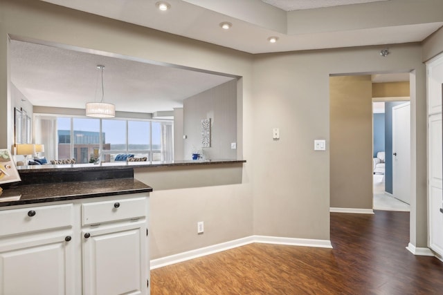 kitchen featuring white cabinets, a textured ceiling, dark stone countertops, dark hardwood / wood-style floors, and decorative light fixtures