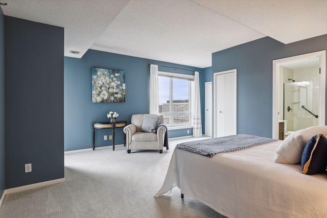 bedroom with a closet, ensuite bathroom, a textured ceiling, and light colored carpet