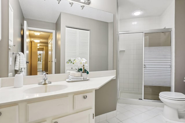 bathroom with a textured ceiling, toilet, a shower with shower door, vanity, and tile patterned floors