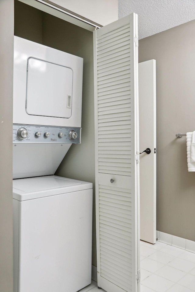 washroom with a textured ceiling and stacked washer and clothes dryer