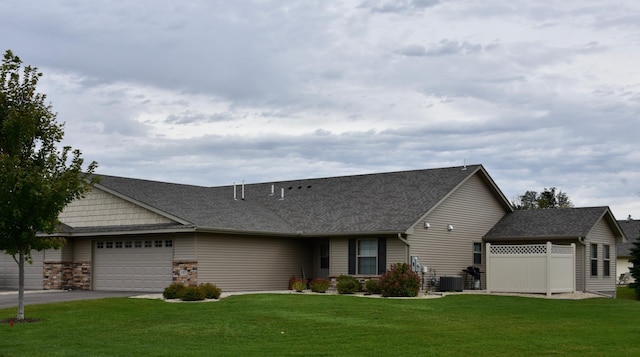 view of front of property featuring a garage, a front yard, and central AC