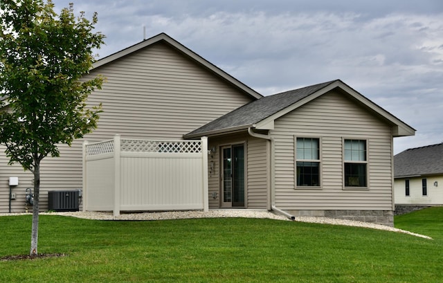 rear view of property featuring a lawn and central AC