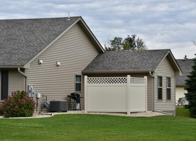 rear view of property featuring central AC unit and a lawn