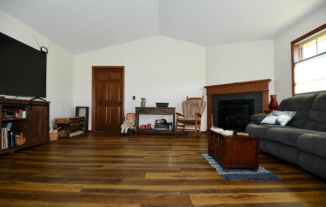 living room featuring dark hardwood / wood-style floors, vaulted ceiling, and a tile fireplace