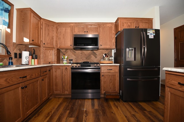 kitchen with dark wood-type flooring, backsplash, appliances with stainless steel finishes, and sink