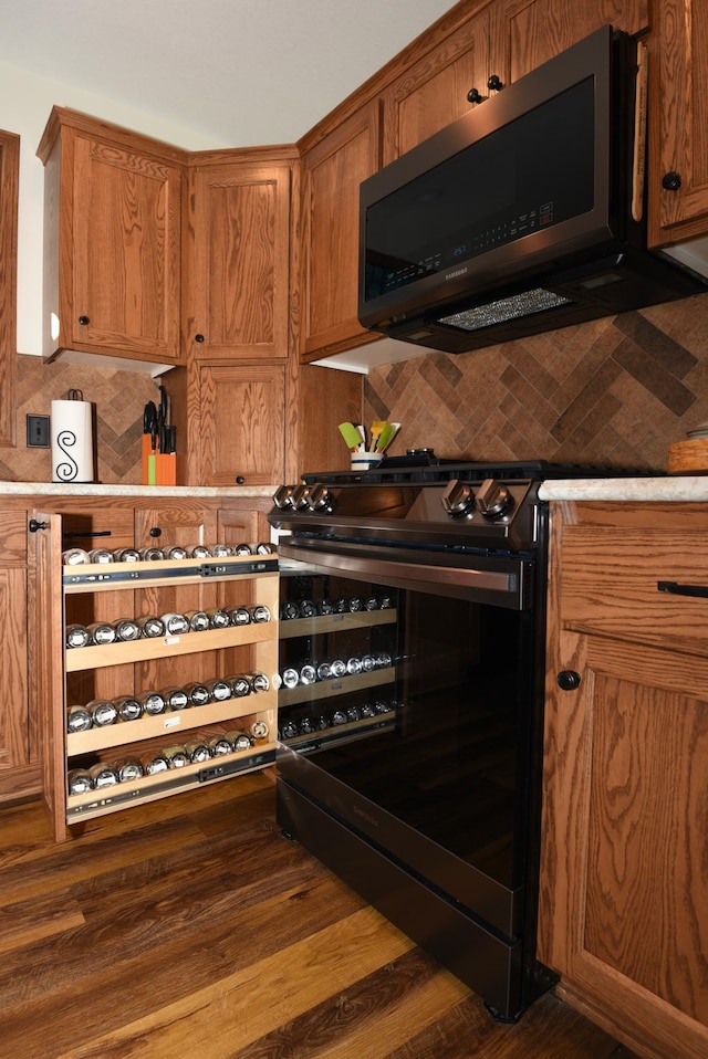 interior space featuring black gas range, dark hardwood / wood-style floors, and tasteful backsplash