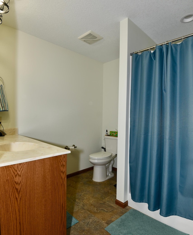 bathroom featuring vanity, toilet, and a textured ceiling