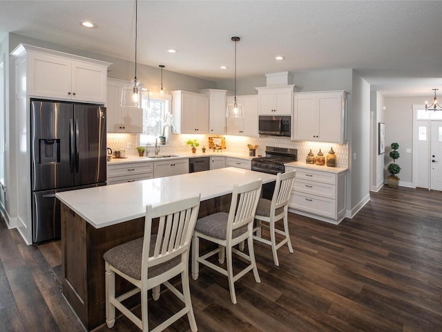 kitchen with stainless steel appliances, dark hardwood / wood-style floors, hanging light fixtures, and a kitchen island