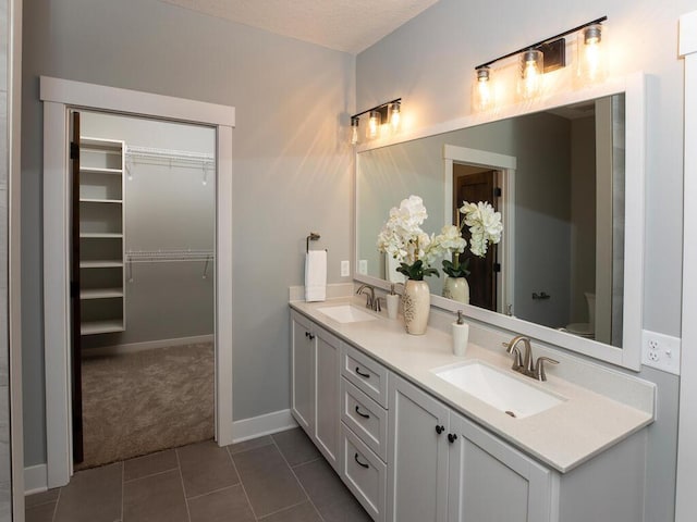 bathroom featuring tile patterned flooring, a textured ceiling, vanity, and toilet