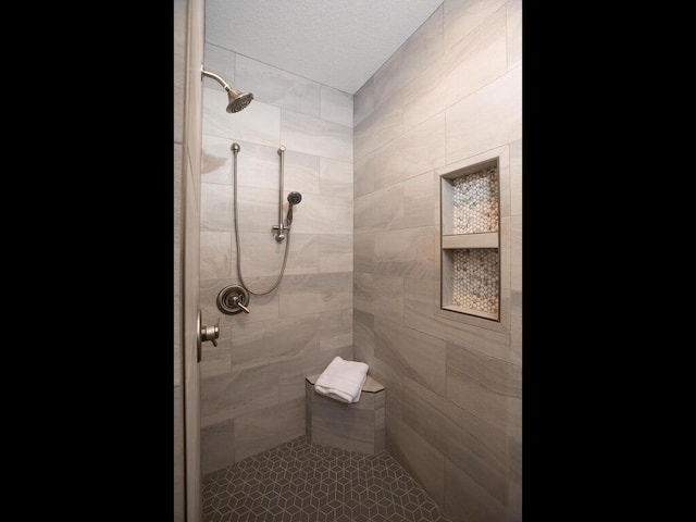 bathroom featuring a textured ceiling and tiled shower