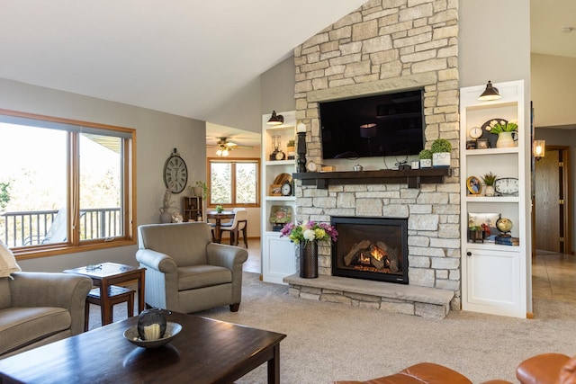 living room featuring high vaulted ceiling, a stone fireplace, ceiling fan, built in features, and light colored carpet