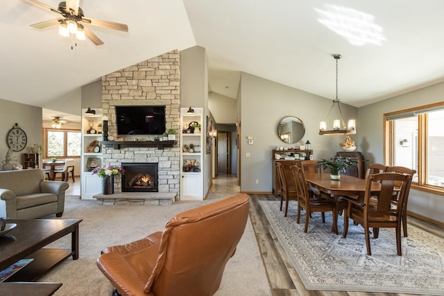 living room with ceiling fan with notable chandelier, light hardwood / wood-style floors, a stone fireplace, and high vaulted ceiling