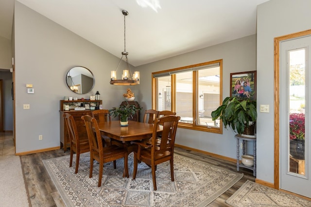 dining room featuring wood-type flooring, lofted ceiling, and a notable chandelier