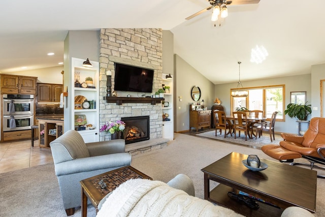 living room featuring ceiling fan with notable chandelier, a stone fireplace, vaulted ceiling, built in features, and light colored carpet