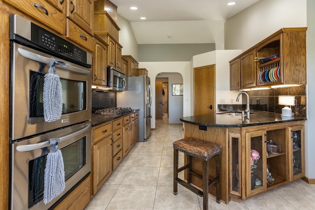 kitchen featuring sink, stainless steel appliances, vaulted ceiling, decorative backsplash, and light tile patterned floors