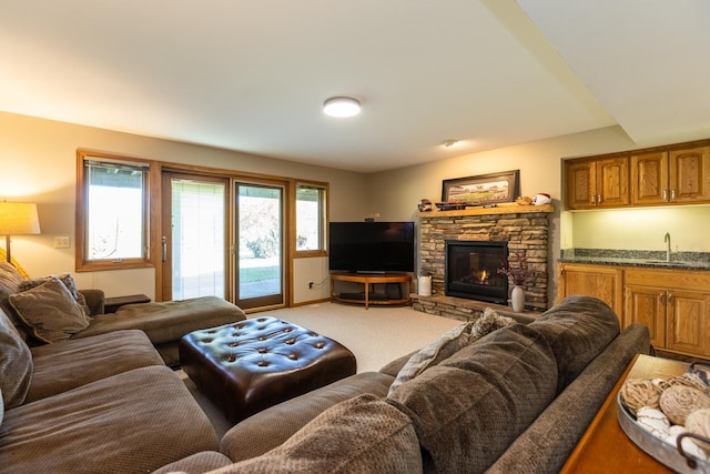 living room featuring carpet flooring, a stone fireplace, and sink