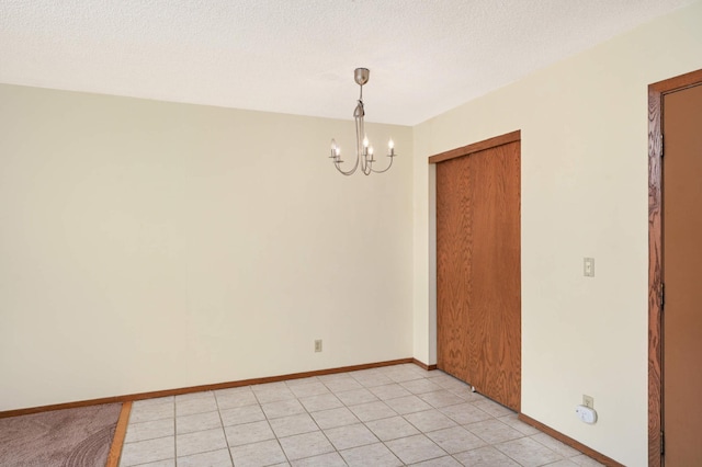 empty room featuring light tile patterned flooring, a chandelier, and a textured ceiling