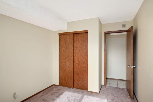 unfurnished bedroom featuring light carpet and a closet