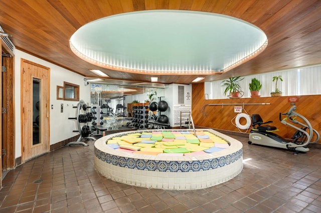 recreation room with wooden walls and dark tile patterned floors