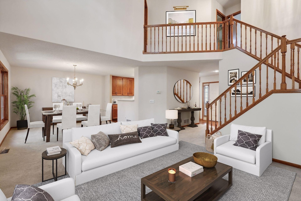 carpeted living room with a towering ceiling and a chandelier