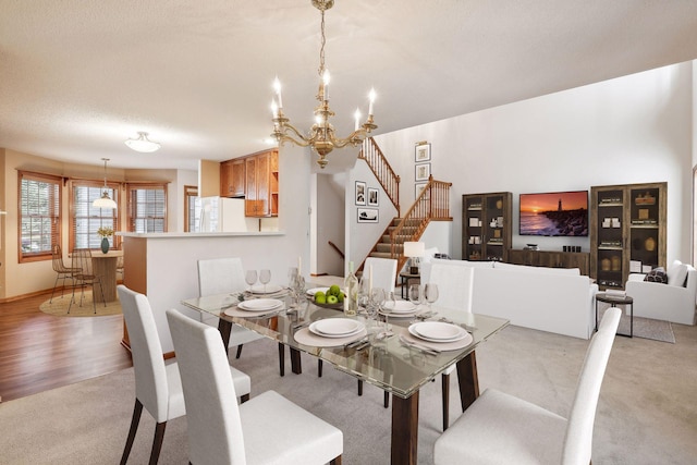 dining area with an inviting chandelier, light wood-type flooring, and a textured ceiling