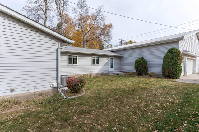 view of side of property featuring cooling unit, a garage, and a lawn