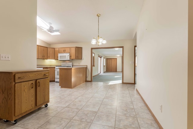 kitchen featuring white appliances, decorative light fixtures, light tile patterned floors, lofted ceiling with skylight, and ceiling fan with notable chandelier