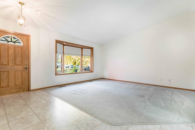 foyer entrance with lofted ceiling, a chandelier, and light carpet