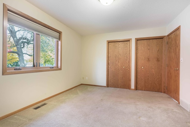 unfurnished bedroom featuring multiple closets and carpet flooring