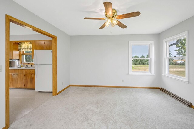 spare room with light carpet, ceiling fan, baseboard heating, and sink