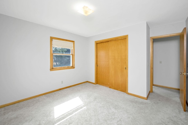 unfurnished bedroom featuring light carpet and a closet