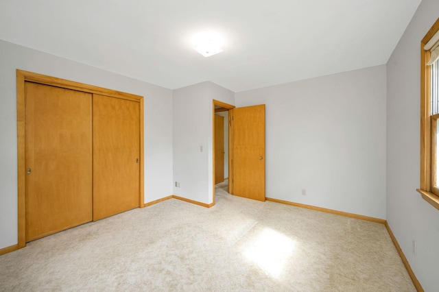 unfurnished bedroom featuring light carpet and a closet