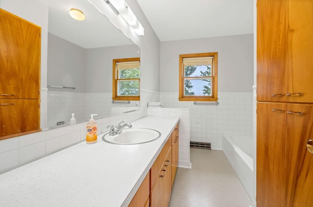 bathroom with tile walls, vanity, and a bathing tub