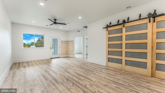 interior space with ceiling fan, light hardwood / wood-style flooring, and a barn door