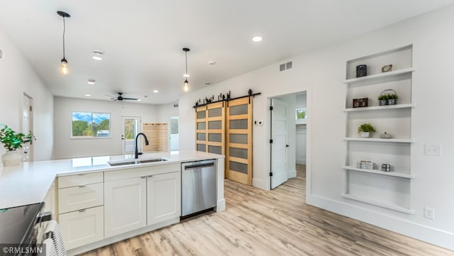 kitchen featuring sink, white cabinets, hanging light fixtures, a barn door, and appliances with stainless steel finishes