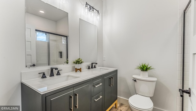 bathroom with a shower with door, hardwood / wood-style flooring, vanity, and toilet