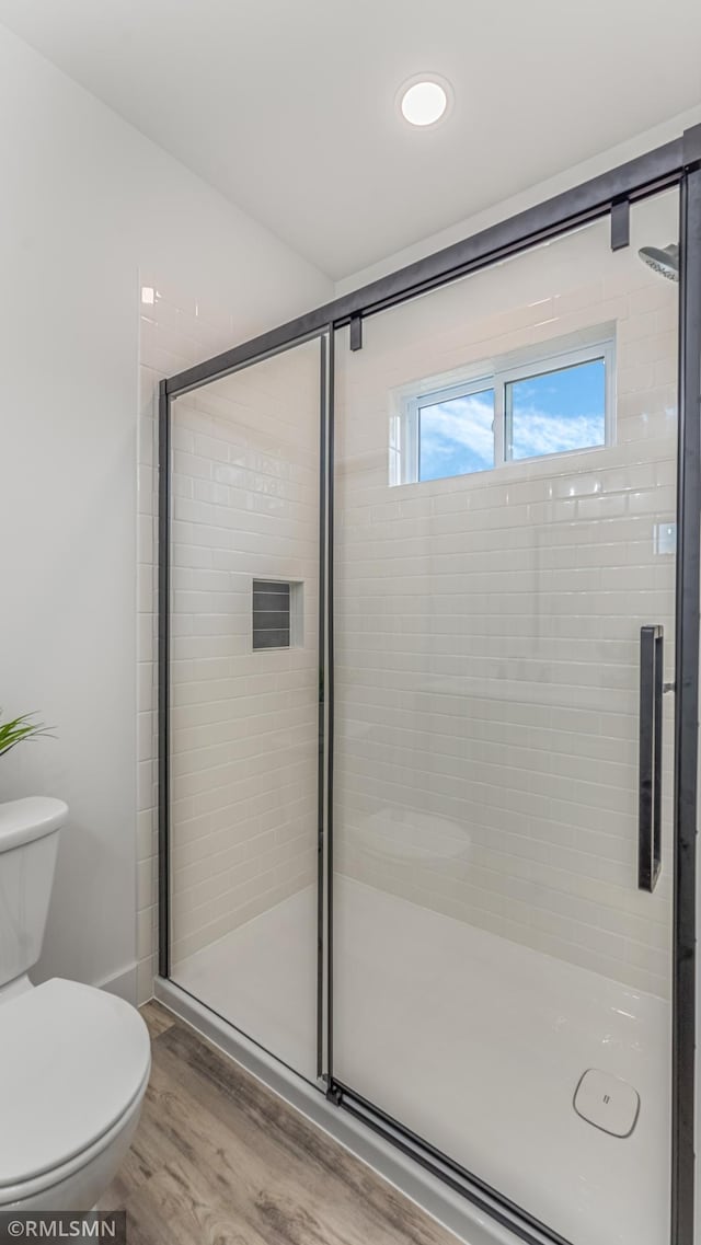 bathroom with hardwood / wood-style floors, toilet, and an enclosed shower