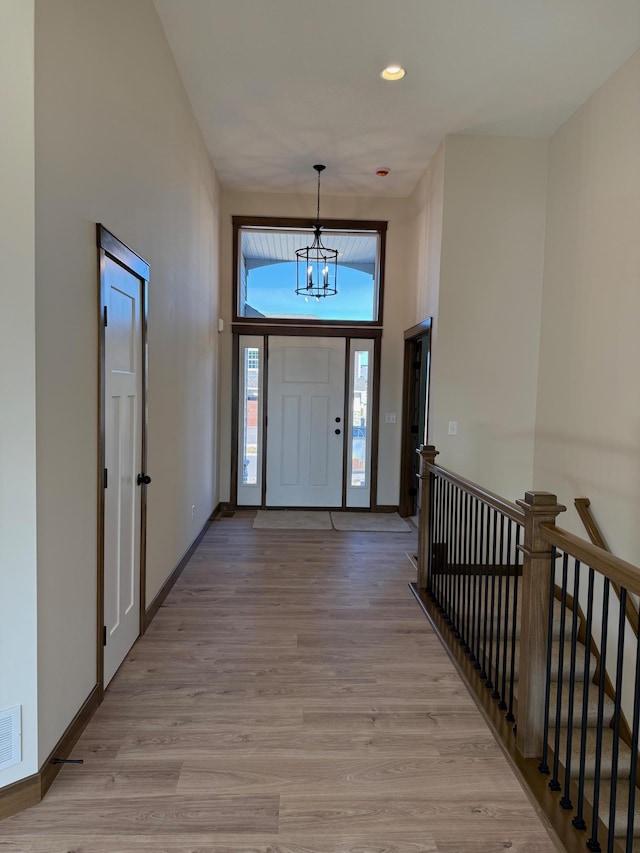 13077 Opal St NE, Blaine, MN 55449 - foyer entrance with light wood finished floors, a notable chandelier, baseboards, and a towering ceiling