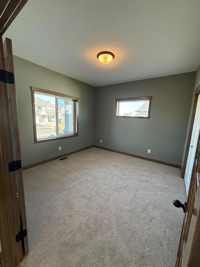 13077 Opal St NE, Blaine, MN 55449 - unfurnished bedroom featuring multiple windows, baseboards, visible vents, and carpet floors