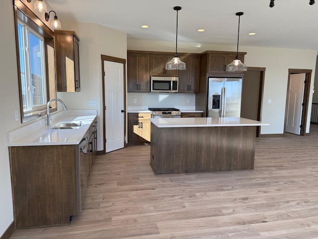 13077 Opal St NE, Blaine, MN 55449 - kitchen featuring a kitchen island, a sink, light countertops, dark brown cabinets, and appliances with stainless steel finishes