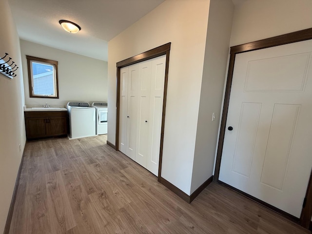 13077 Opal St NE, Blaine, MN 55449 - hallway with washing machine and dryer, baseboards, light wood-style floors, and a sink