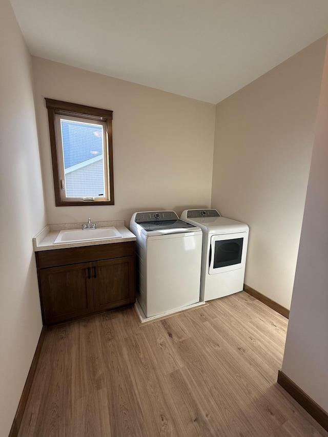 13077 Opal St NE, Blaine, MN 55449 - laundry room with baseboards, light wood finished floors, cabinet space, a sink, and washer and clothes dryer