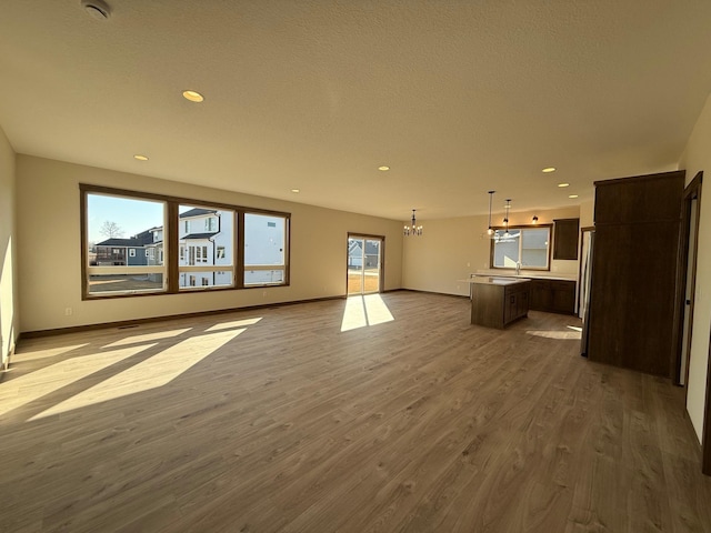13077 Opal St NE, Blaine, MN 55449 - unfurnished living room featuring dark wood-type flooring, baseboards, recessed lighting, a notable chandelier, and a textured ceiling