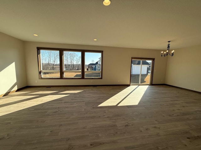 13077 Opal St NE, Blaine, MN 55449 - spare room featuring a notable chandelier, a healthy amount of sunlight, baseboards, and dark wood-style flooring